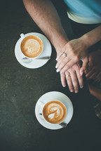 a couple holding hands and coffee cups 