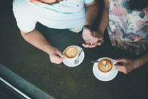 a couple holding hands and drinking coffee 