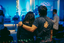 a couple with arms around each other during a worship service 