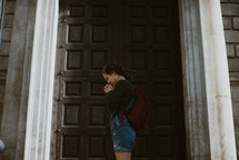 a young woman praying at church doors 