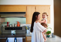 a mother talking to her toddler daughter in a kitchen 