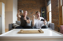two guys playing video games on a couch. 