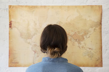a woman looking at a world map on a wall. 