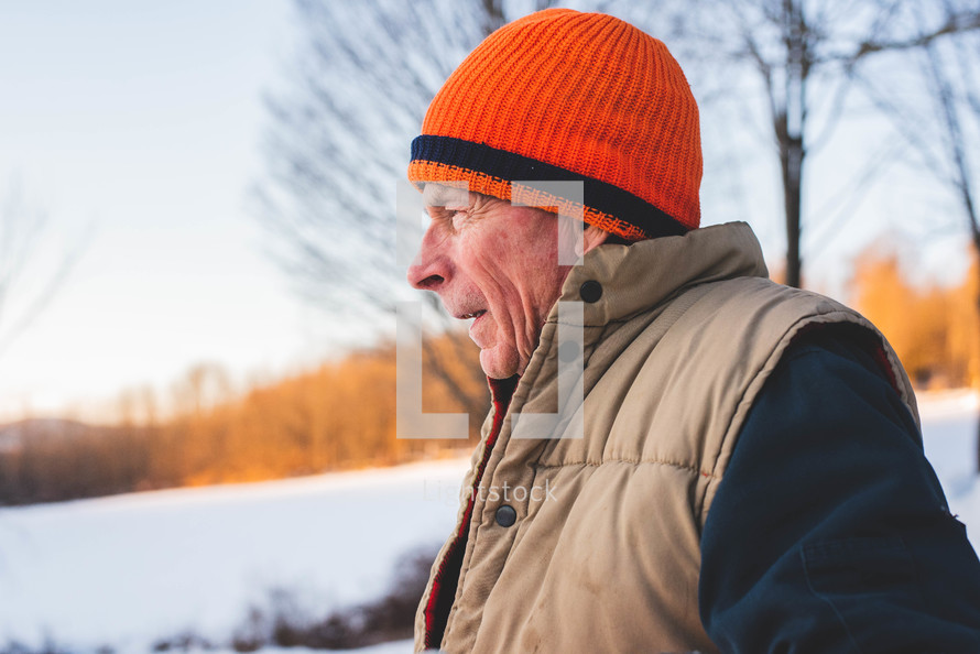 an elderly man standing outdoors in snow 