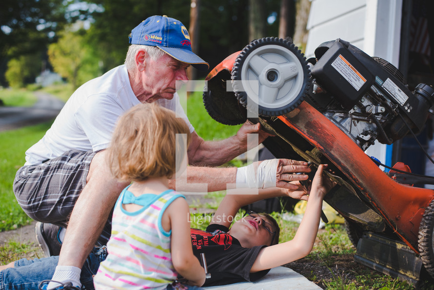 grandfather and his grandchildren fixing a lawnmower 