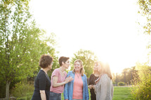women standing in a backyard talking 