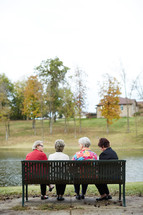 elderly women sitting on a bench talking 