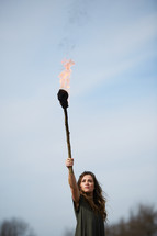 a woman holding up a burning torch 