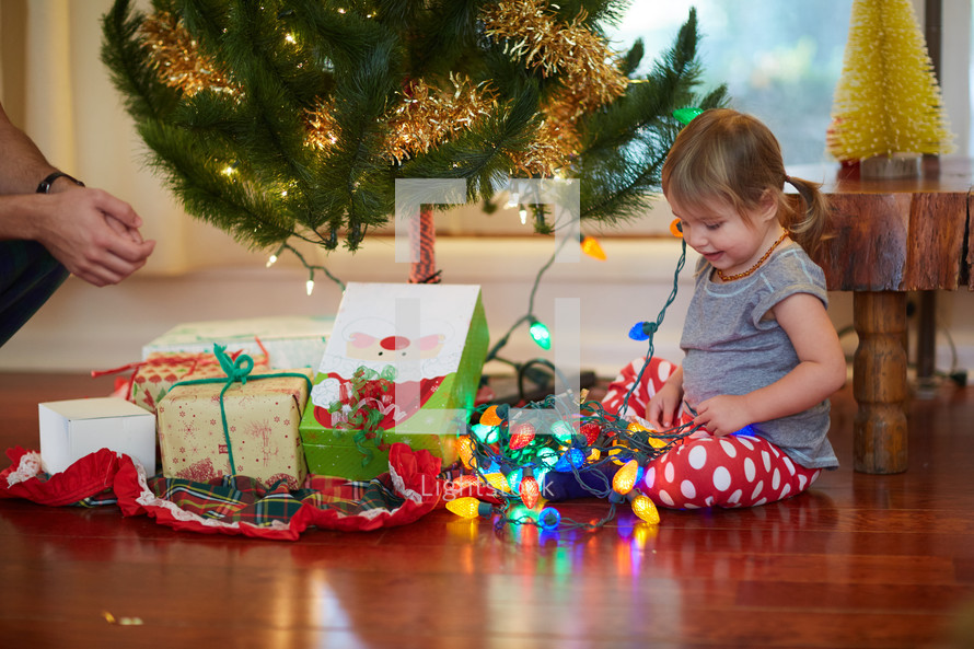 a girl opening a present under the Christmas tree