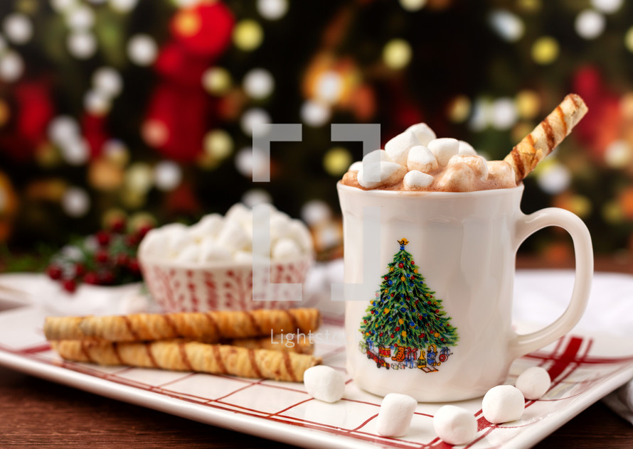 Hot Chocolate in a Christmas Cup Piled High with Marshmallows with Christmas Tree in Background