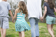 a family walking holding hands in the back yard 