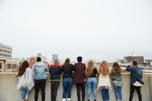 group of teens looking over a railing on a parking deck 