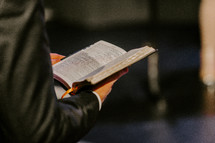 Close up of hands holding an open Bible.