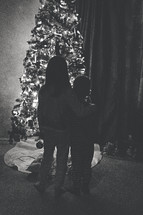 silhouettes of children standing in front of a Christmas tree 