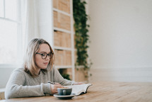 a woman sitting reading a Bible over coffee 