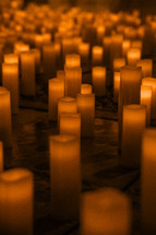 Lots of candles on a church floor, candle light glowing orange