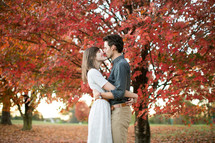 a couple hugging outdoors in fall leaves 