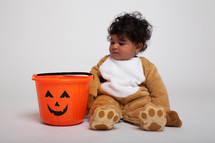 toddler boy in a Halloween costume with a jack-0-latern candy bucket 