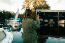Woman lure fishing in a marina setting, pike fishing, fishing rod and fishing reel course angling, tweed jacket, winter coat, outdoors sports activities, 