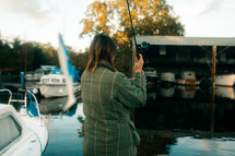 Woman lure fishing in a marina setting, pike fishing, fishing rod and fishing reel course angling, tweed jacket, winter coat, outdoors sports activities, 