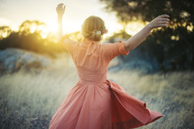 a woman in a dress dancing in a field 