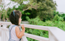 a little girl looking over a railing 