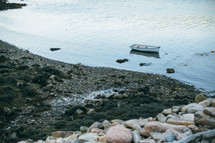 a boat anchored in shallow water along a shore 