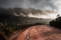fog rising over a dirt road 
