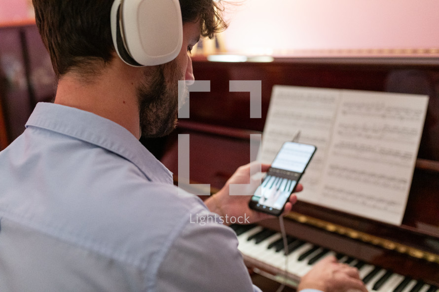 Man learning piano lessons with remote smartphone connection