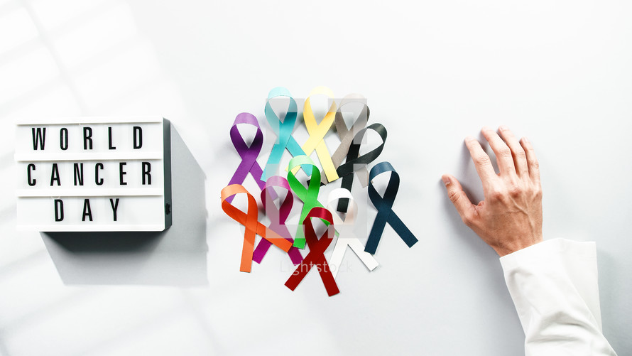 world cancer awareness day ribbon with a hand of a doctor