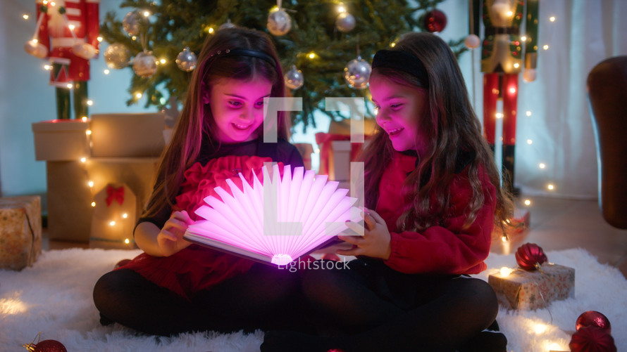 Little Girls opening a magic book with light