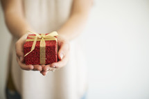 a woman holding out a wrapped Christmas gift 