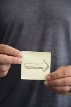 man holding a post-it note with an arrow 