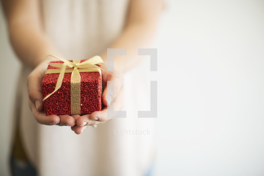 a woman holding out a wrapped Christmas gift 