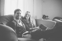 Smiling couple sitting on a sofa.