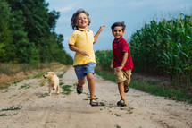 Happy Kids Running Together With Golden Retriever Puppy On Green Nature Background. Smiling Brothers.