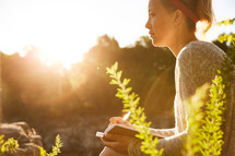 a woman journaling outdoors at sunset 