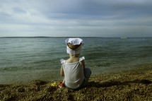 a little girl sitting on a shore 