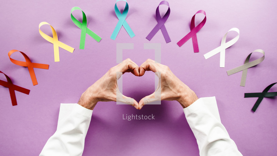 world cancer awareness day ribbons and hand heart shape of a doctor