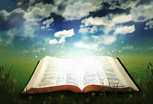 twinkling light from a glowing Bible lying in grass under a blue sky