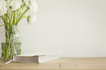 white flowers in a vase and Bible on a table 