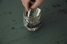 putting cash in a tithe savings jar 