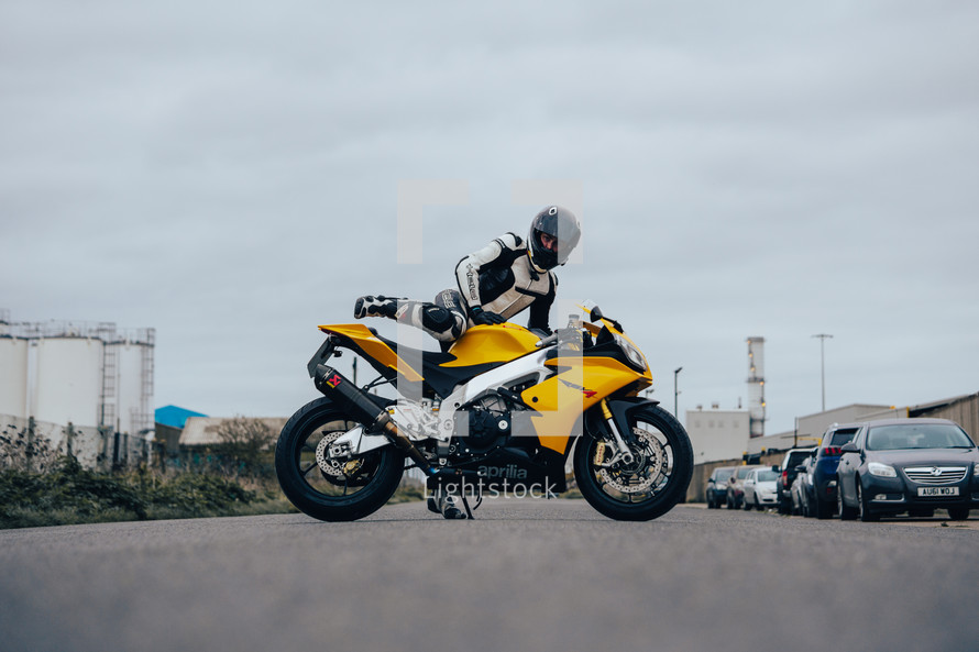 Aprilia RSV4 sports motorbike, superbike motorcycle, yellow racing colours with a female rider in full racing leathers and helmet