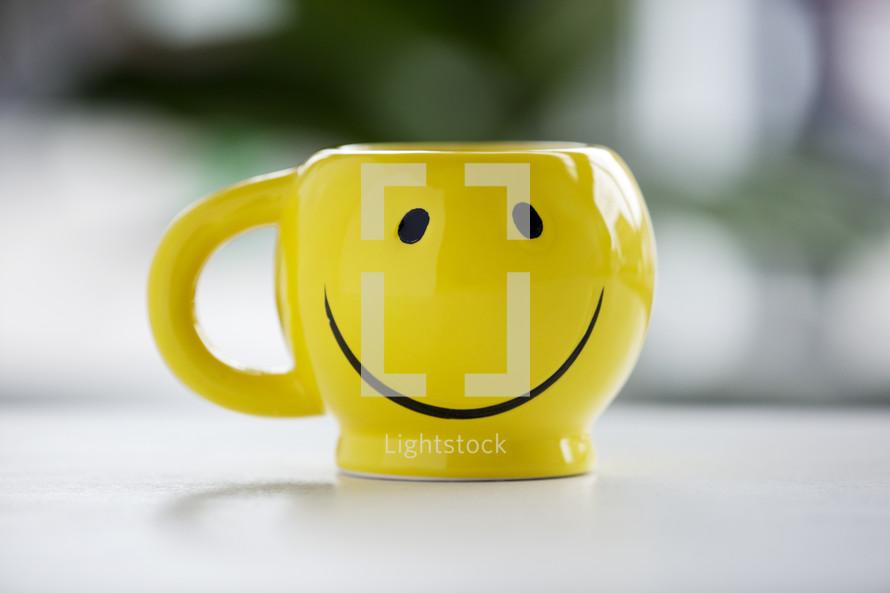 smiley face coffee mug on a table.