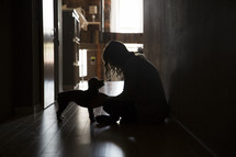 a woman sitting in dark hallway with her dog 