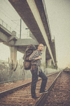 man backpacking standing on train tracks