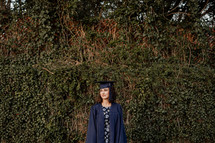 female graduate standing in front of vines 