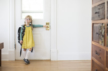girl child standing at a door with a book bag - first day of school 