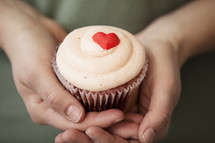hands holding a Valentine's day cupcake 
