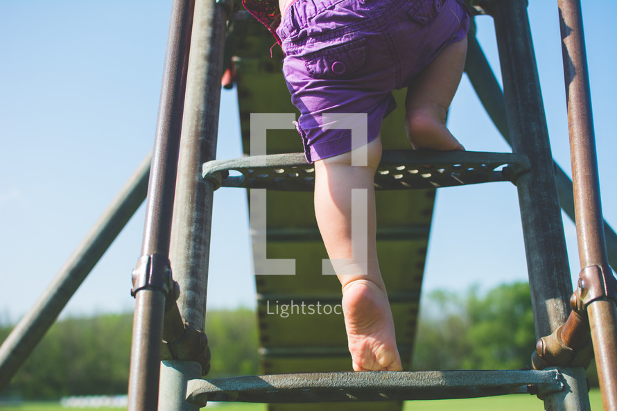 a toddler climbing up a slide 